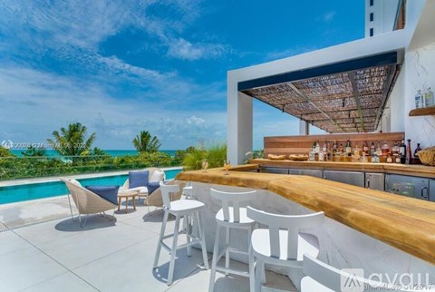 A modern outdoor dining area with a pool and a view of the ocean.