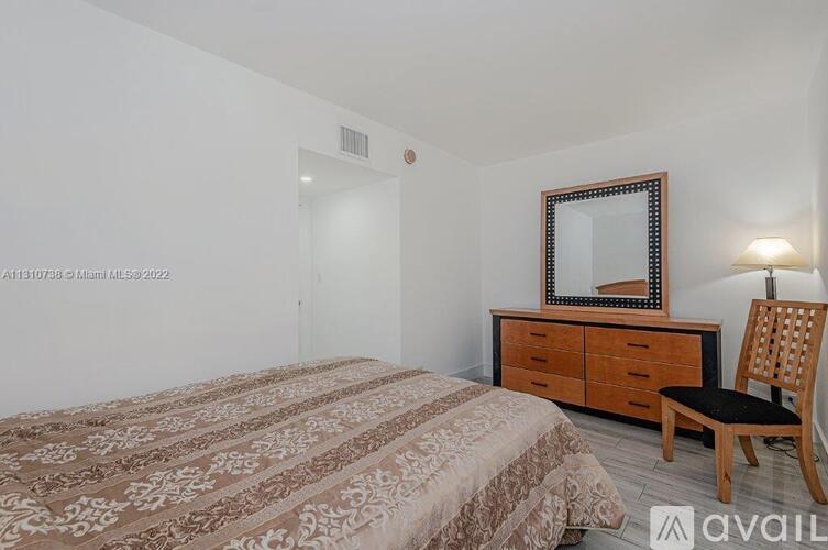 A bedroom with a bed, a chair, and a dresser with a mirror above it.