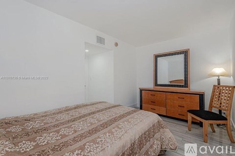 A bedroom with a bed, a chair, and a dresser with a mirror above it.