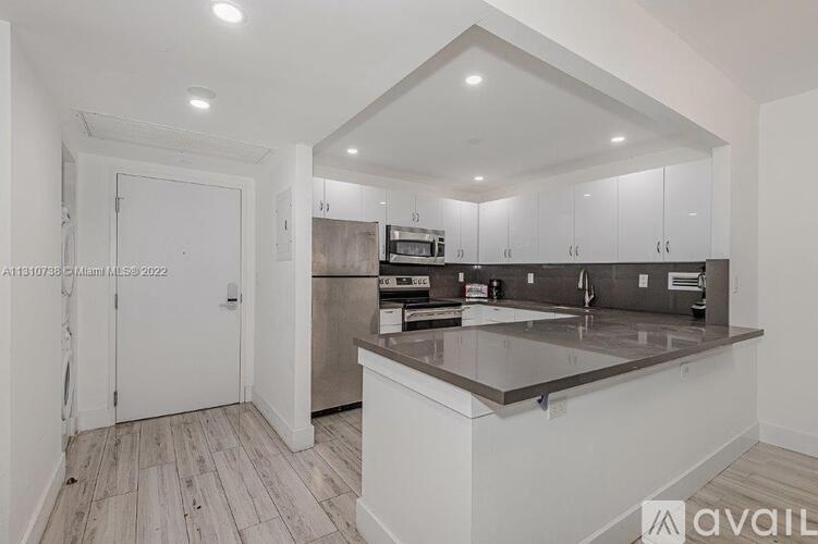 A kitchen with white cabinets and a marble countertop.