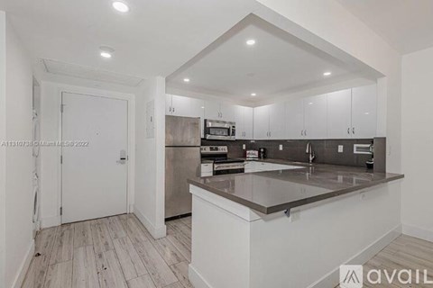 A kitchen with white cabinets and a marble countertop.