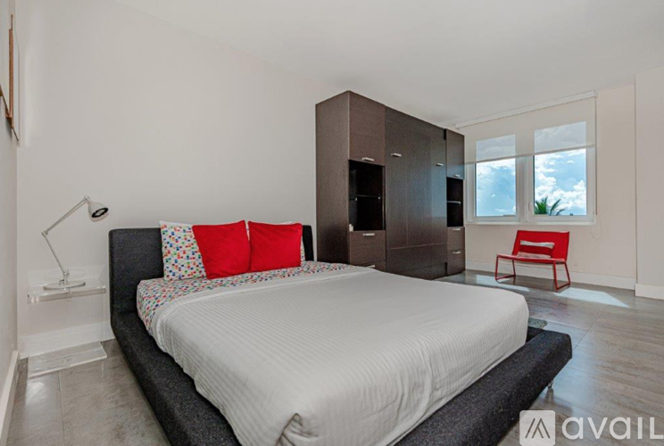 A bedroom with a large bed and a red chair.