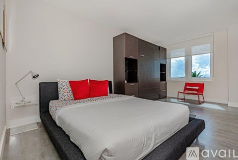 A bedroom with a large bed and a red chair.