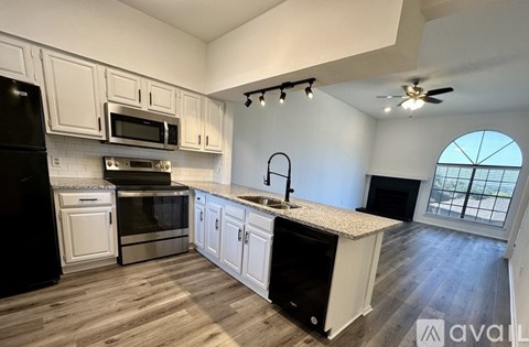 A kitchen with white cabinets and black appliances.