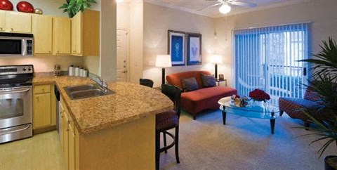 A kitchen with a red couch and a table with a vase of flowers on it.