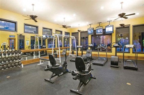 A gym with a variety of equipment including treadmills, weights, and exercise machines.