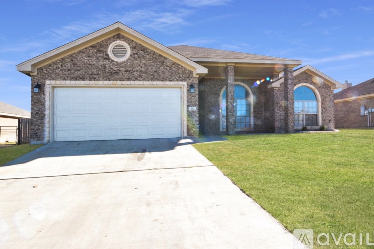A house with a garage and a tree in front.