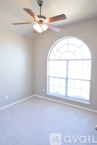 A room with a ceiling fan and a large arched window.