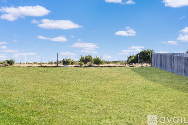 A field with a fence and a tree in the foreground.