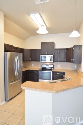 A kitchen with a stainless steel refrigerator and black cabinets.