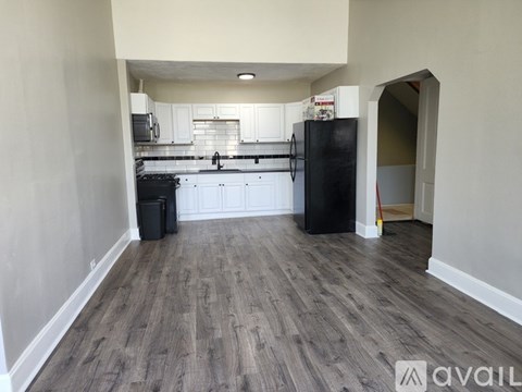 A kitchen with a black fridge and a wooden floor.