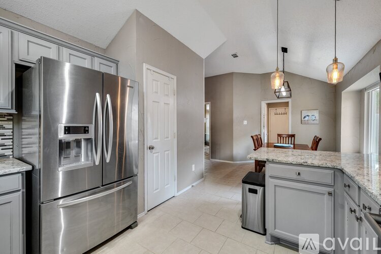 A kitchen with a stainless steel refrigerator and a marble countertop.