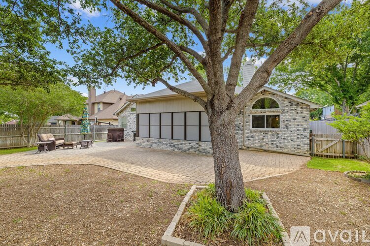 A house with a stone exterior and a large tree in the front yard.