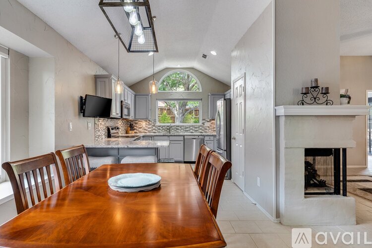 A dining room with a wooden table and chairs is set up with a TV mounted on the wall.