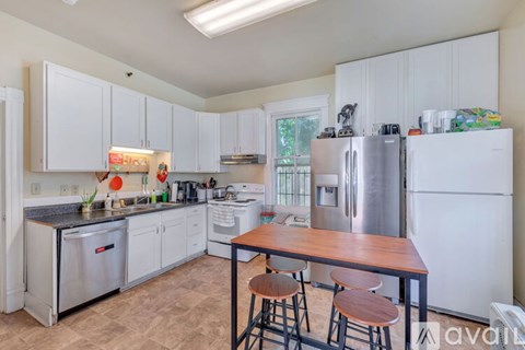 A kitchen with white cabinets and a wooden table.