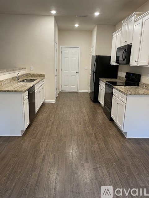 A kitchen with white cabinets and a black refrigerator.