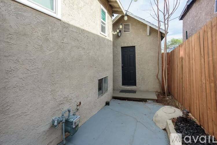A small, beige stucco house with a black door and a small window.