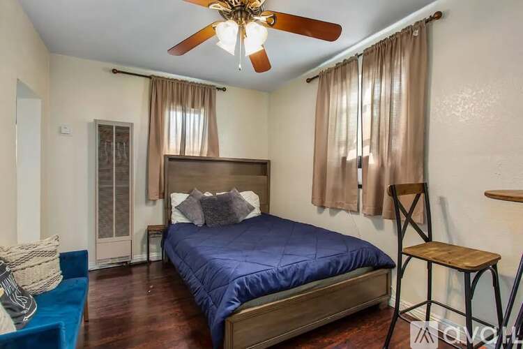 A bedroom with a bed, a chair, and a ceiling fan.