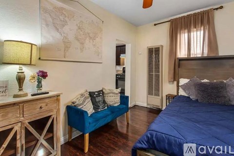 A bedroom with a blue bed and a wooden dresser.