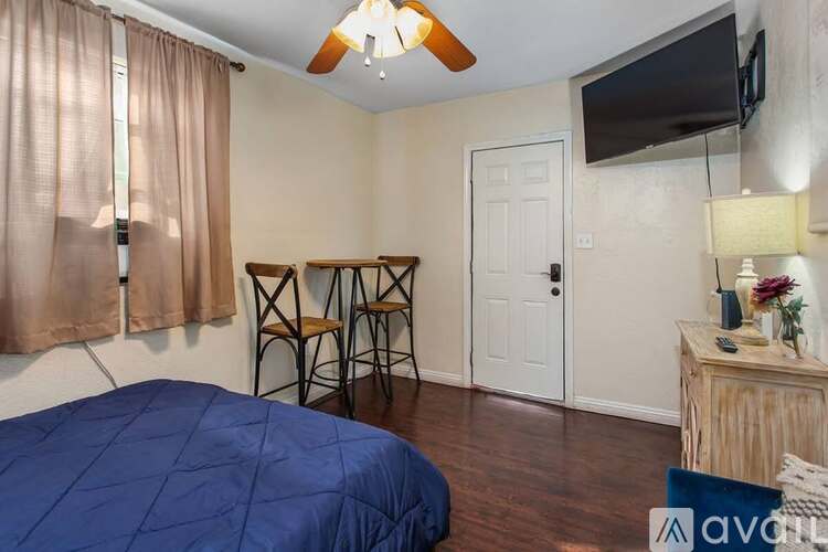 A bedroom with a bed, a wooden table, and a television mounted on the wall.
