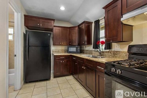 A kitchen with brown cabinets and black appliances.