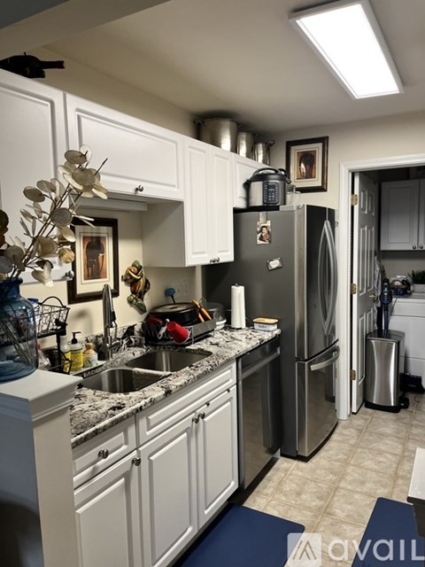 A kitchen with a refrigerator, sink, and cabinets.