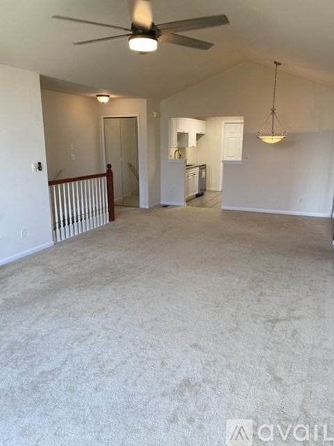 A spacious room with a ceiling fan and a hanging light fixture.