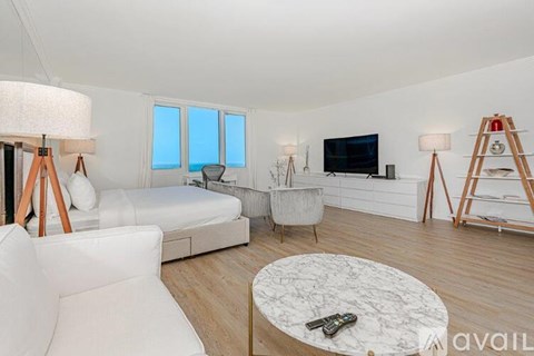 A living room with a white couch, a white chair, a white coffee table, and a white floor.