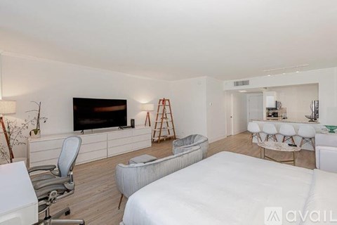 A bedroom with a white bed and a television on the wall.