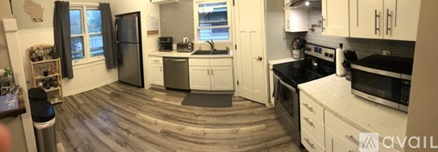 A kitchen with white cabinets and a black refrigerator.