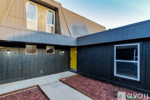 A modern house with a black exterior and a yellow door.