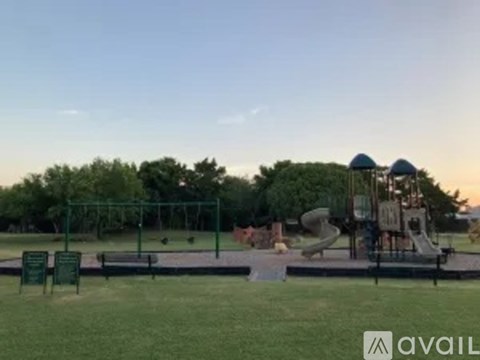 A playground with a slide and swings is set in a grassy area.