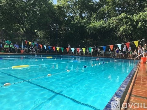 A swimming pool with people in the background and a line of flags hanging above the pool.