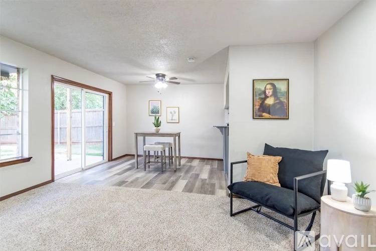 A living room with a black sofa, a small table, a ceiling fan, and a painting on the wall.