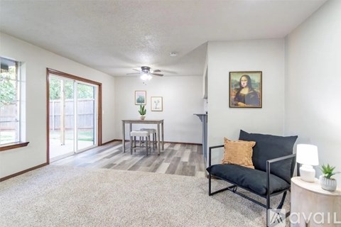 A living room with a black sofa, a small table, a ceiling fan, and a painting on the wall.