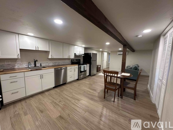 A kitchen with a black refrigerator and wooden beams on the ceiling.