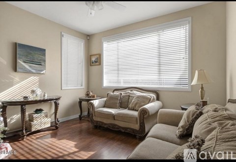 A living room with a couch, a table, and a painting on the wall.