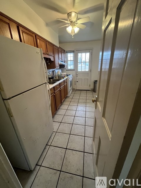 A kitchen with a white refrigerator and wooden cabinets.