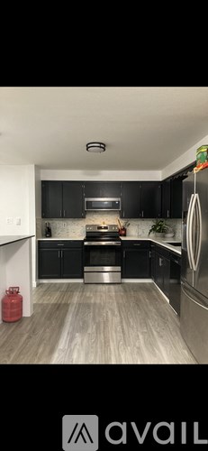 A kitchen with black cabinets and a wooden floor.