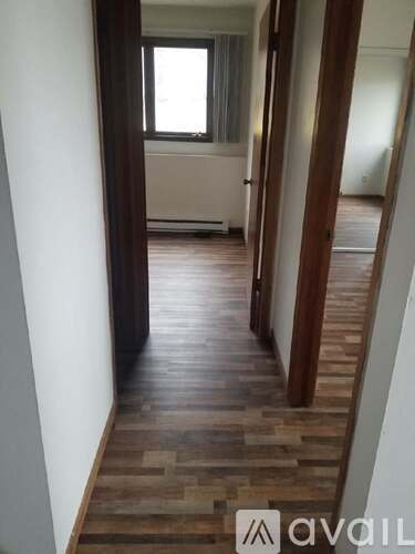 A hallway with wooden floors and white walls.
