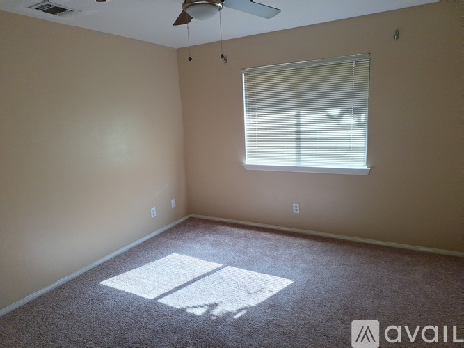 A room with a carpeted floor, a ceiling fan, and a window with blinds.