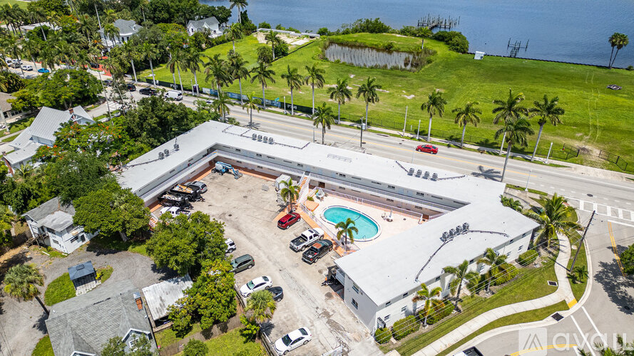 An aerial view of a building with a pool and cars parked in front.