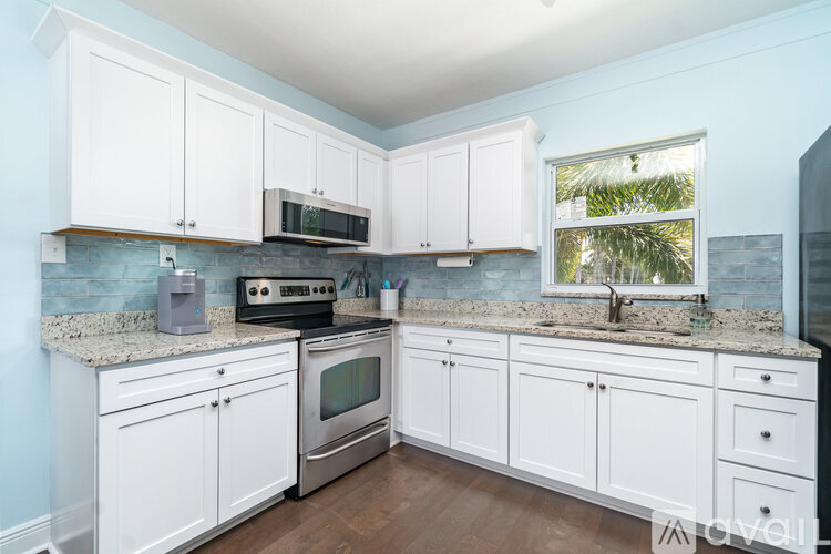 A kitchen with white cabinets and a granite countertop.