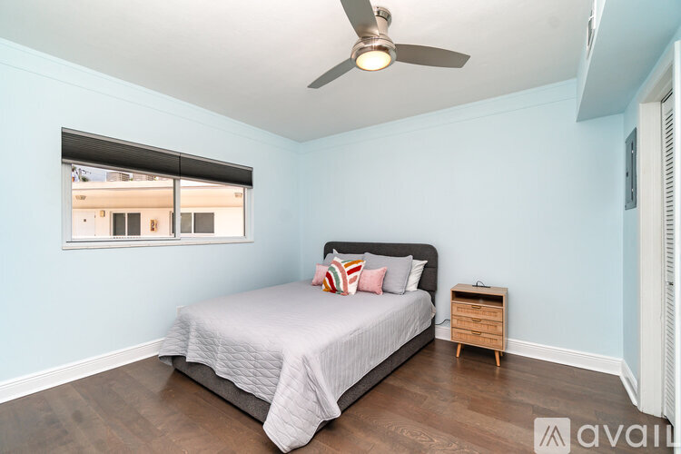 A bedroom with a bed, nightstand, and window.
