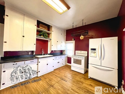 A kitchen with white cabinets and a white refrigerator.