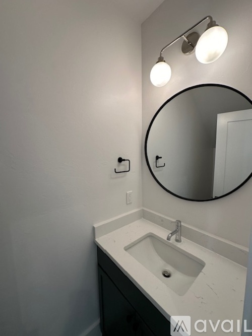 A bathroom with a sink, mirror, and light fixture.