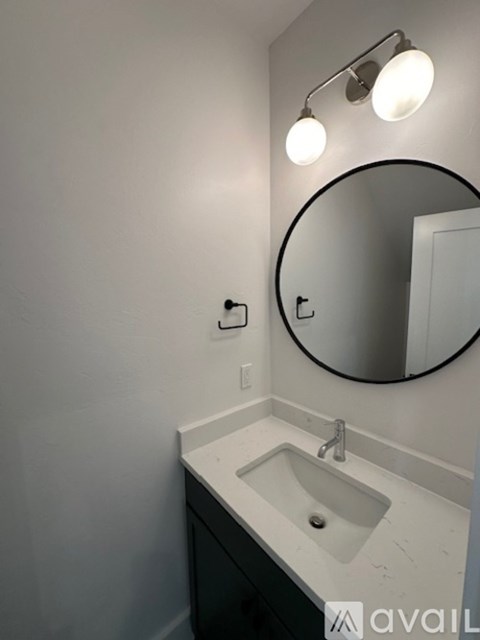 A bathroom with a sink, mirror, and light fixture.