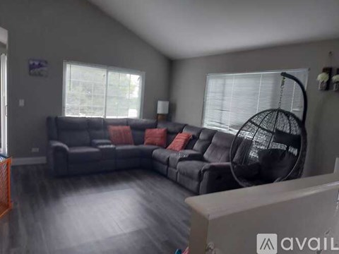 A living room with a grey couch and a black hanging chair.