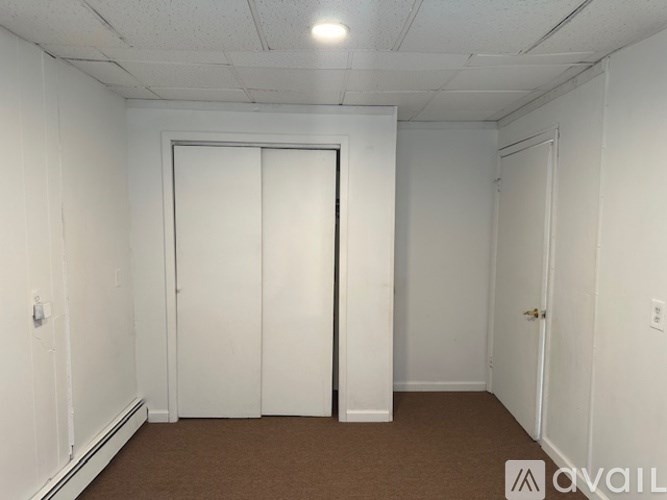 A room with white walls and a brown carpet.