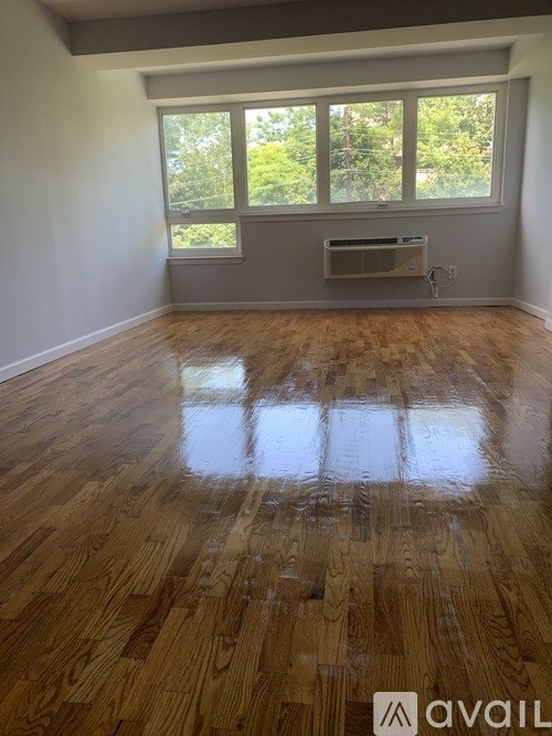 A room with wooden flooring and a window with a view of trees.